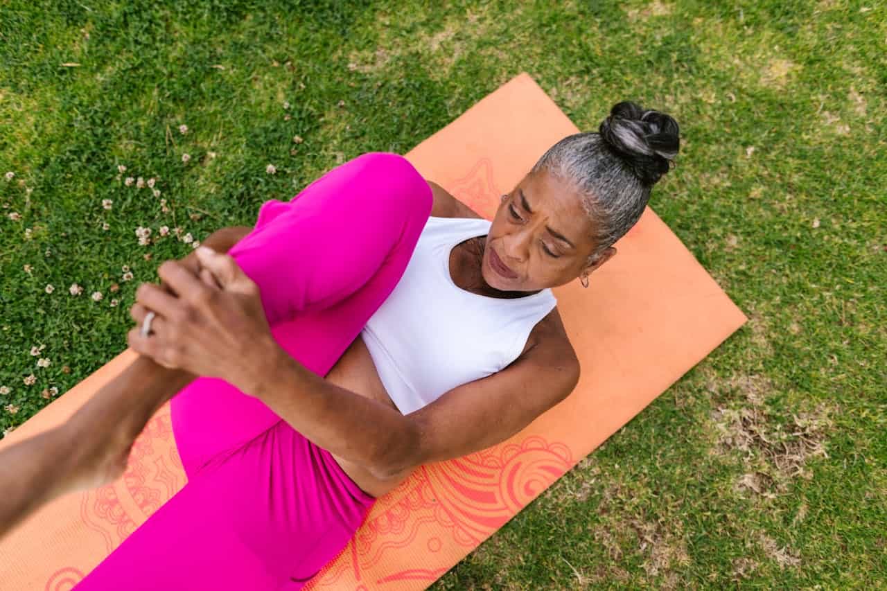Woman practicing outdoor yoga for fitness and wellness on a grassy field.