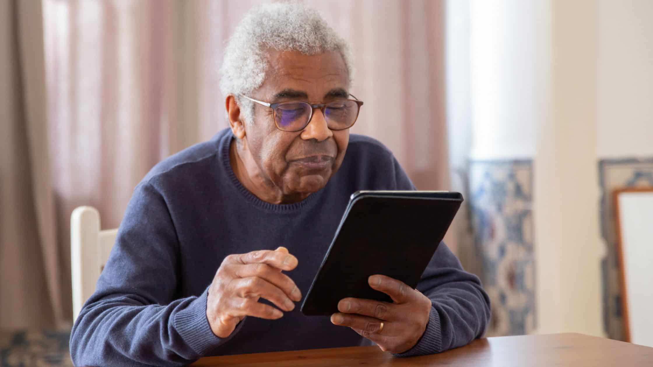 Elderly man using a tablet, focusing on digital technology and senior citizen online engagement.